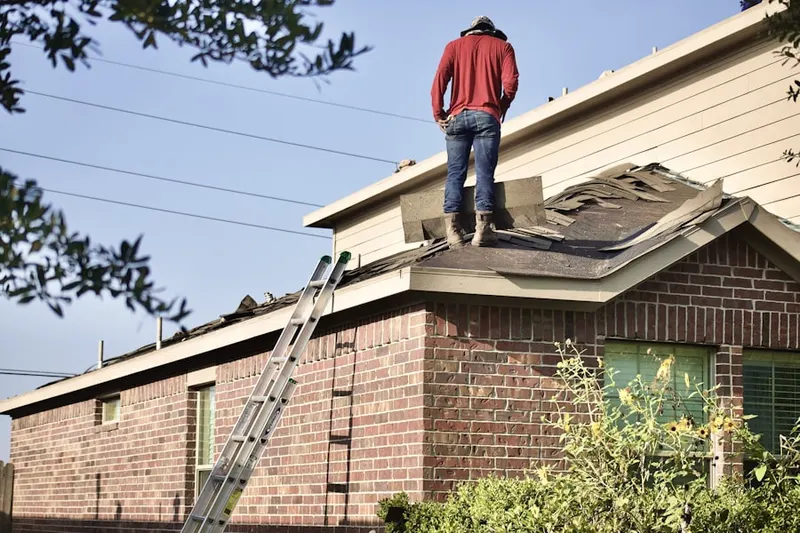 Professional roofer working on a residential roof in Bentley College